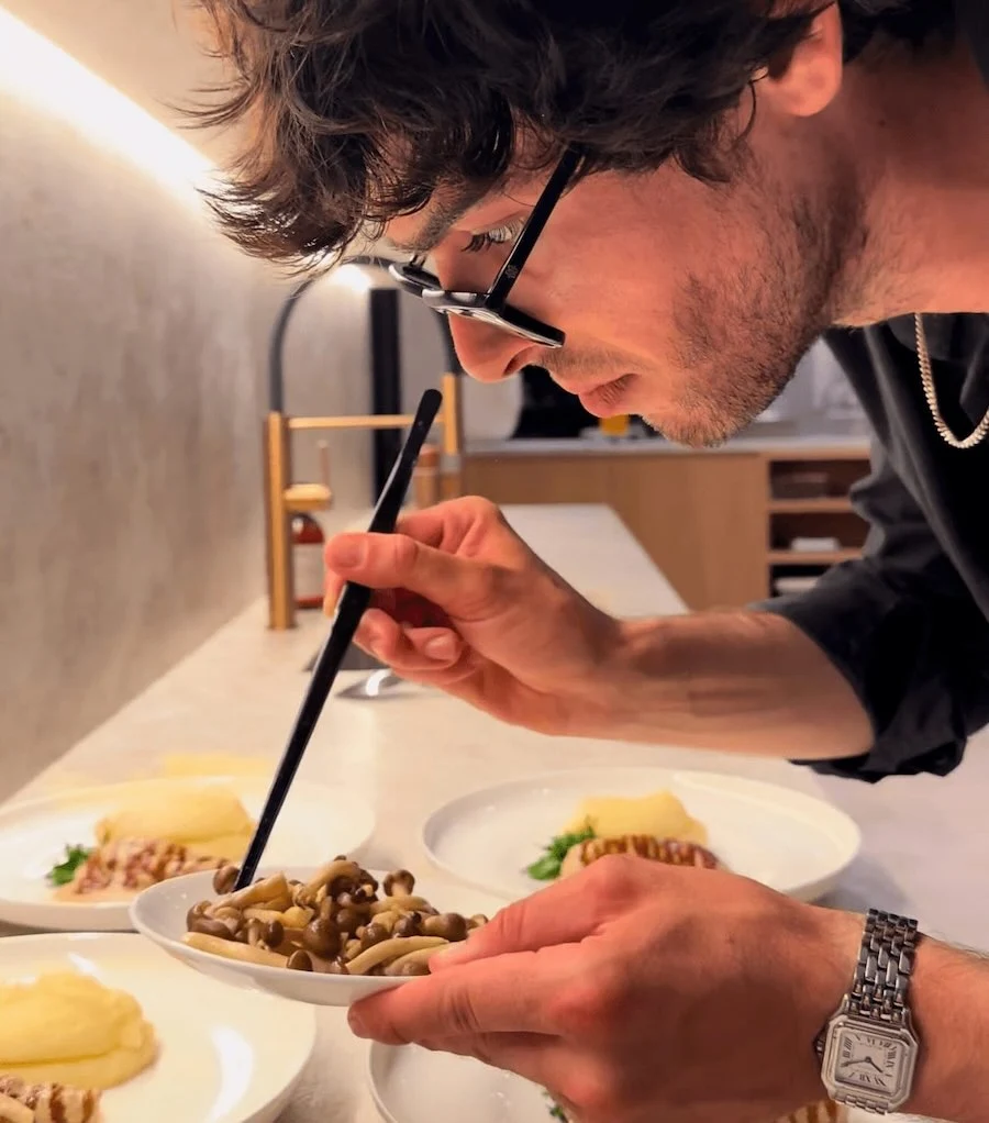 Chef gastronomique dressant un plat avec précision dans sa cuisine.